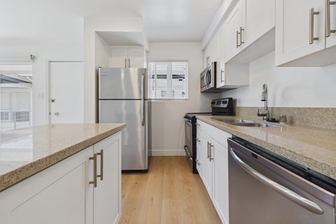 A kitchen with white cabinets and a granite countertop.