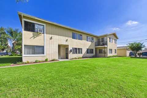 A beige building with a green lawn in front.