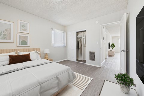 A bedroom with a large bed and a plant on the table.