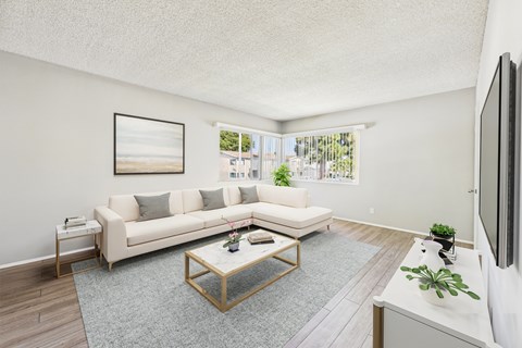 A living room with a white couch and a painting on the wall.