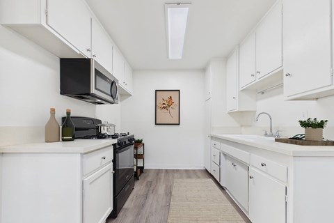 A kitchen with white cabinets and a black stove top oven.