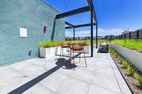 A patio with a table and chairs is in front of a green wall.