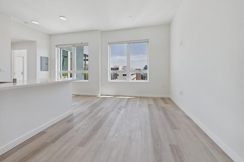 A spacious room with wooden flooring and a large window overlooking a cityscape.