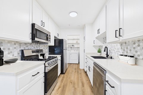 A kitchen with white cabinets and black appliances.