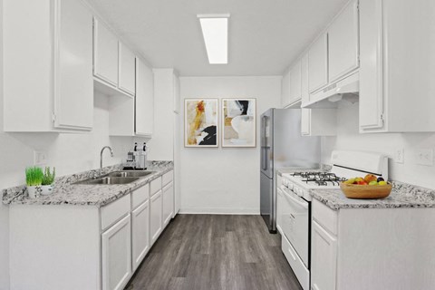 A kitchen with white cabinets and a marble countertop.