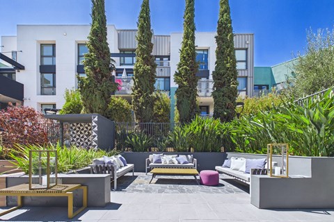 A modern outdoor seating area with a variety of seating options and greenery.