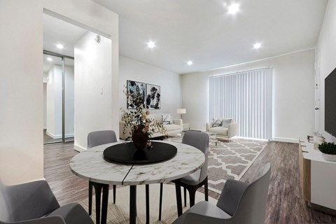 A modern dining room with a round marble table and grey chairs.
