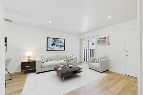 A living room with a white couch, a coffee table, and a painting on the wall.