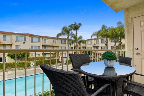 a patio with a table and chairs and a pool in the background