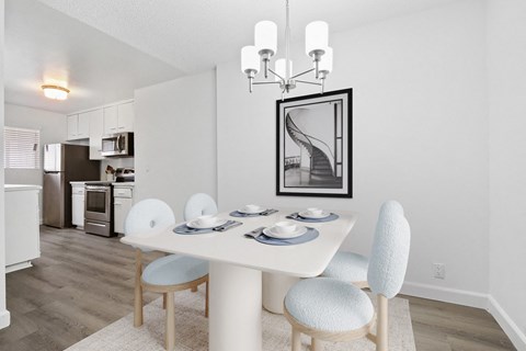 A dining room with a white table and chairs.