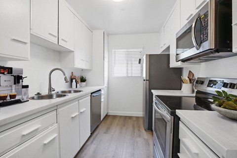 A modern kitchen with white cabinets and stainless steel appliances.