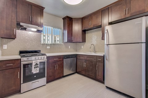 A kitchen with a stainless steel refrigerator and wooden cabinets.