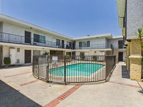 A pool surrounded by a fence in front of a building.