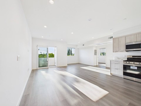 A spacious, well-lit room with a wooden floor and white walls.