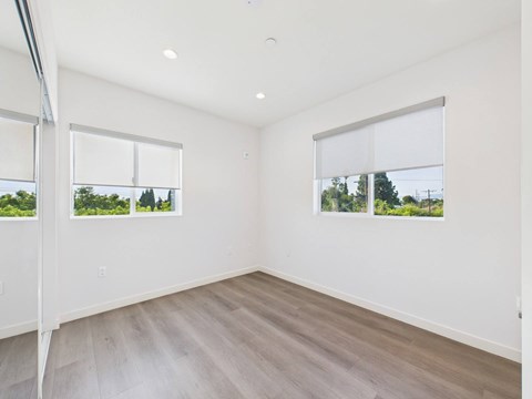 A room with a white wall and a window with a view of trees.