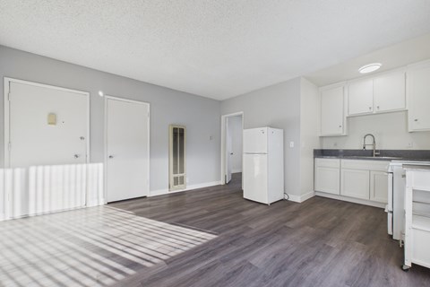 A kitchen with white cabinets and a wooden floor.