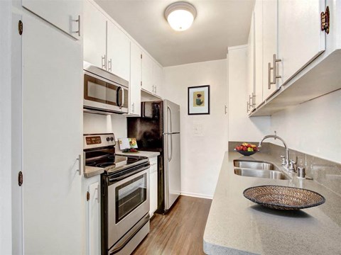 A kitchen with white cabinets and a black countertop.