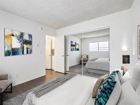 A living room with a white couch and a painting on the wall.