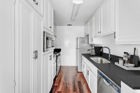 A kitchen with white cabinets and a black countertop.