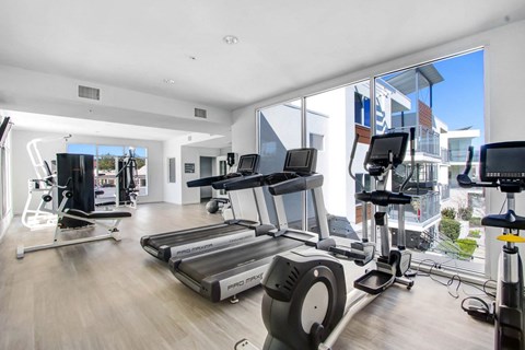 a gym with cardio equipment and windows on the side of a building