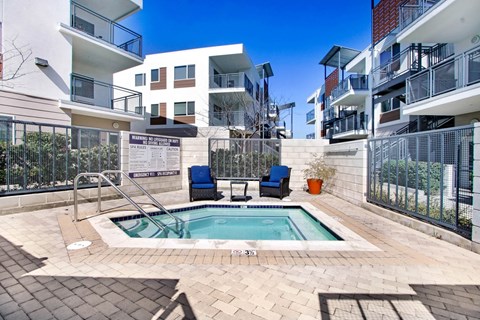 an apartment pool with two chairs in front of an apartment building