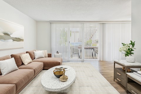 A living room with a brown couch, a coffee table, and a plant.