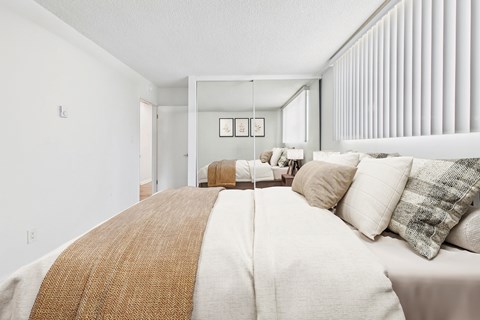 A bedroom with a large bed and a mirror on the wall.