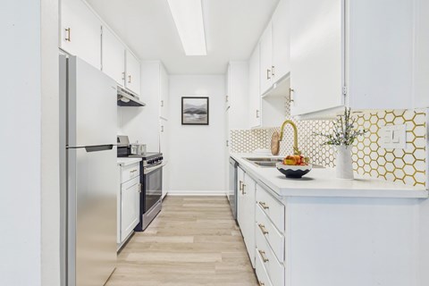 A kitchen with white cabinets and a stainless steel refrigerator.