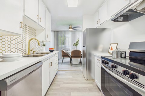 A kitchen with a white tile backsplash and a stainless steel dishwasher.