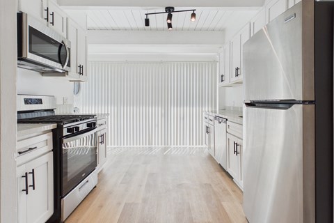 A modern kitchen with white cabinets and stainless steel appliances.