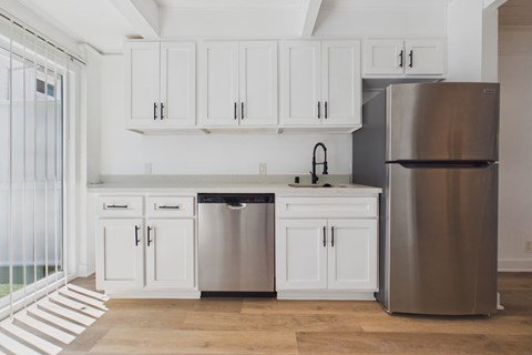 A modern kitchen with white cabinets and a stainless steel refrigerator.