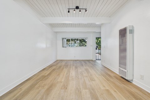 A spacious room with wooden flooring and a ceiling fan.