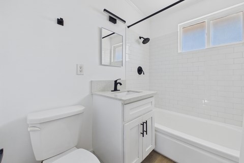 A white bathroom with a toilet, sink, and bathtub.