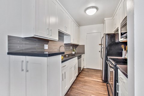 A kitchen with white cabinets and a black countertop.