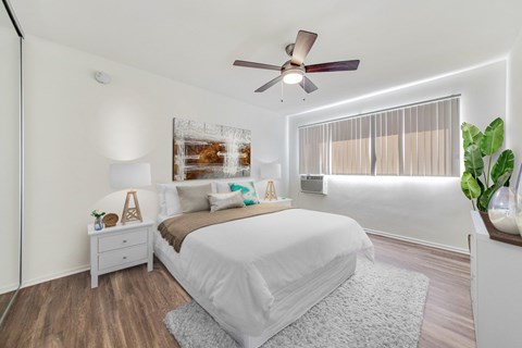 A bedroom with a large bed and a ceiling fan.