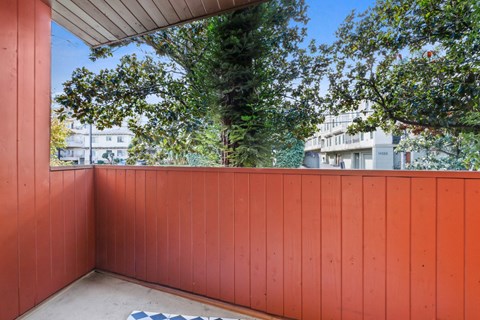 a balcony with a red privacy wall and trees