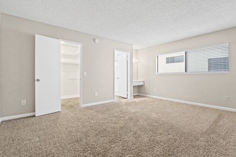 the spacious living room of an apartment with carpet and an open door to the bathroom