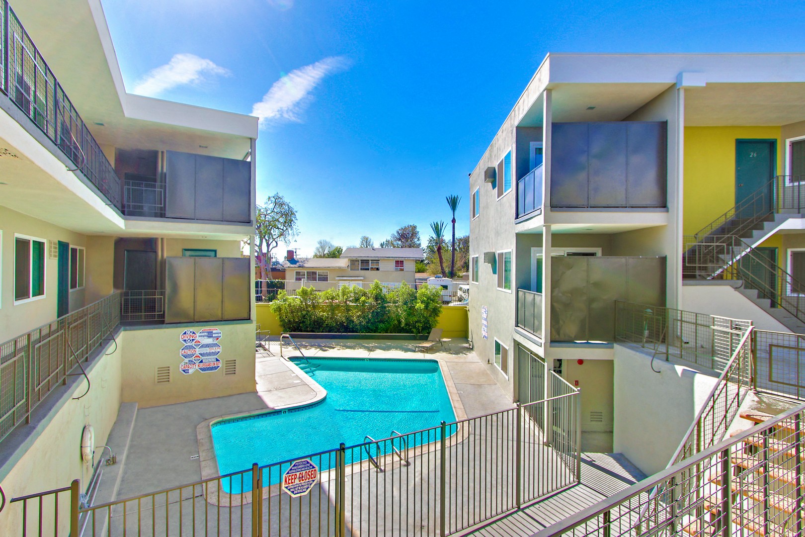 A pool in a fenced in area outside a building.