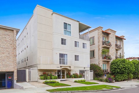 A modern two-story building with a flat roof and a balcony on the second floor.