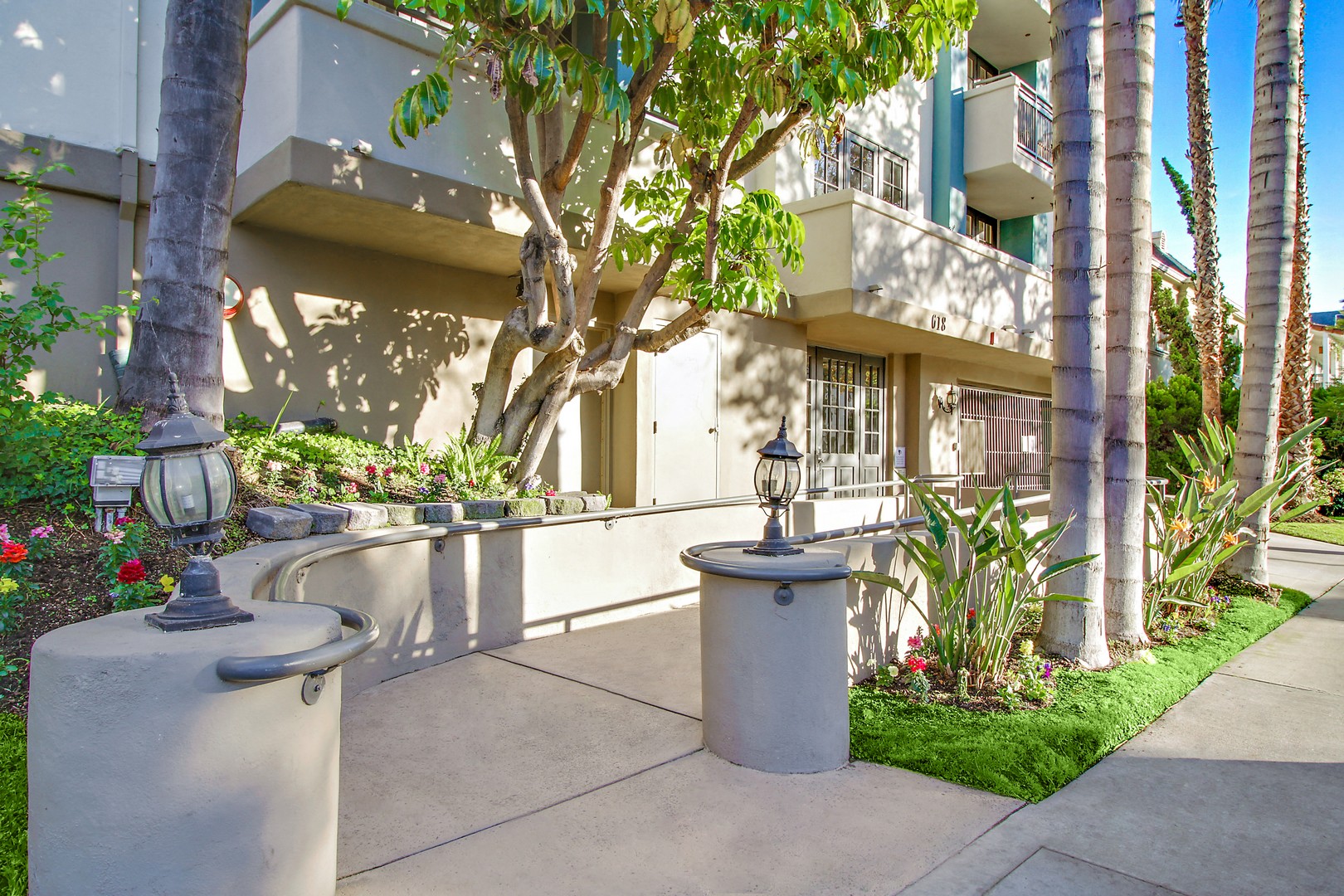 A concrete fountain in front of a building with a tree in the background.