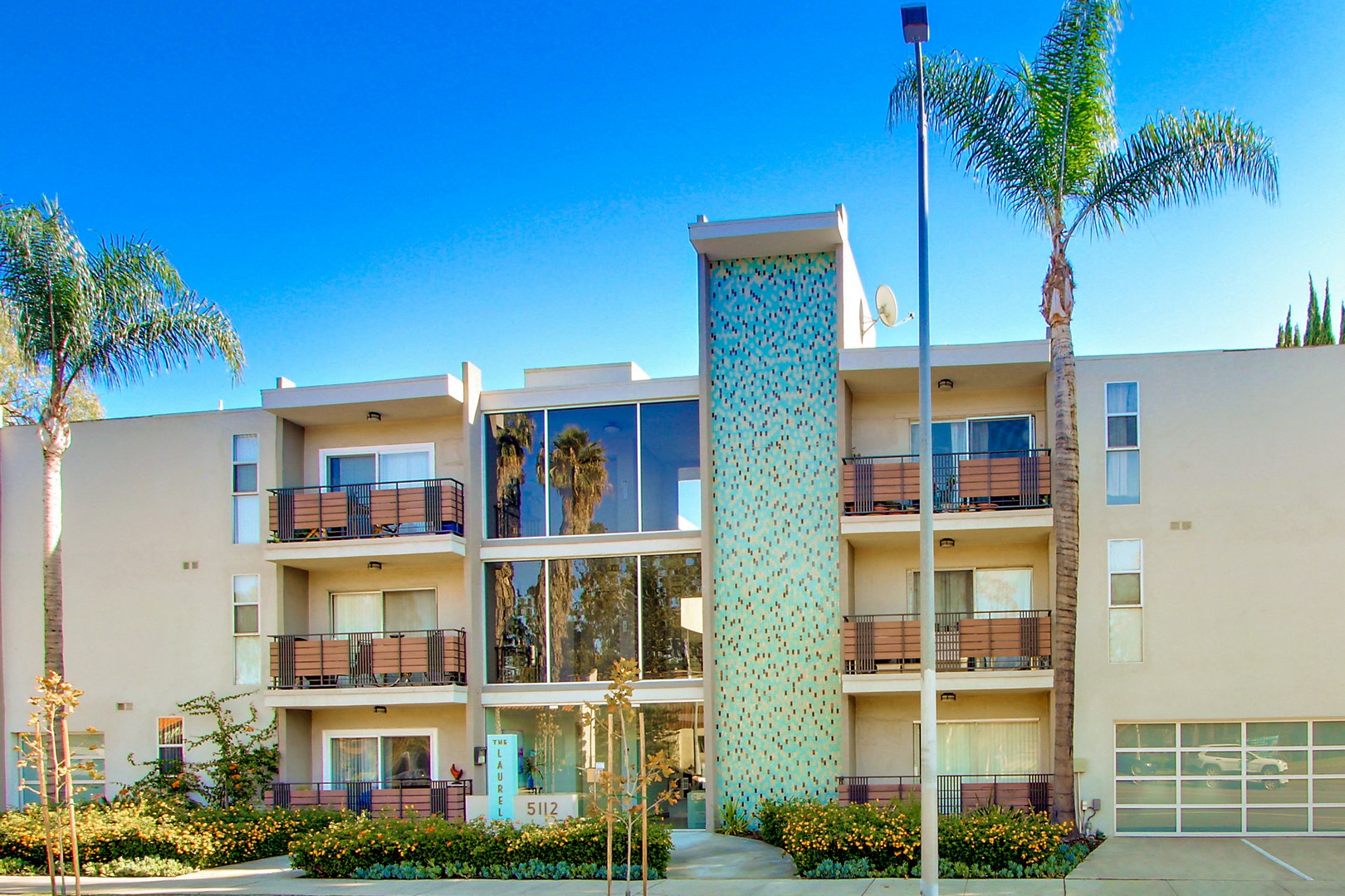A tall building with a blue and white patterned tower in the middle of a sunny day.