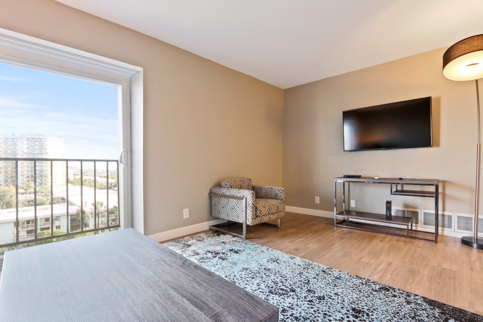 A living room with a grey carpet and a flat screen TV mounted on the wall.