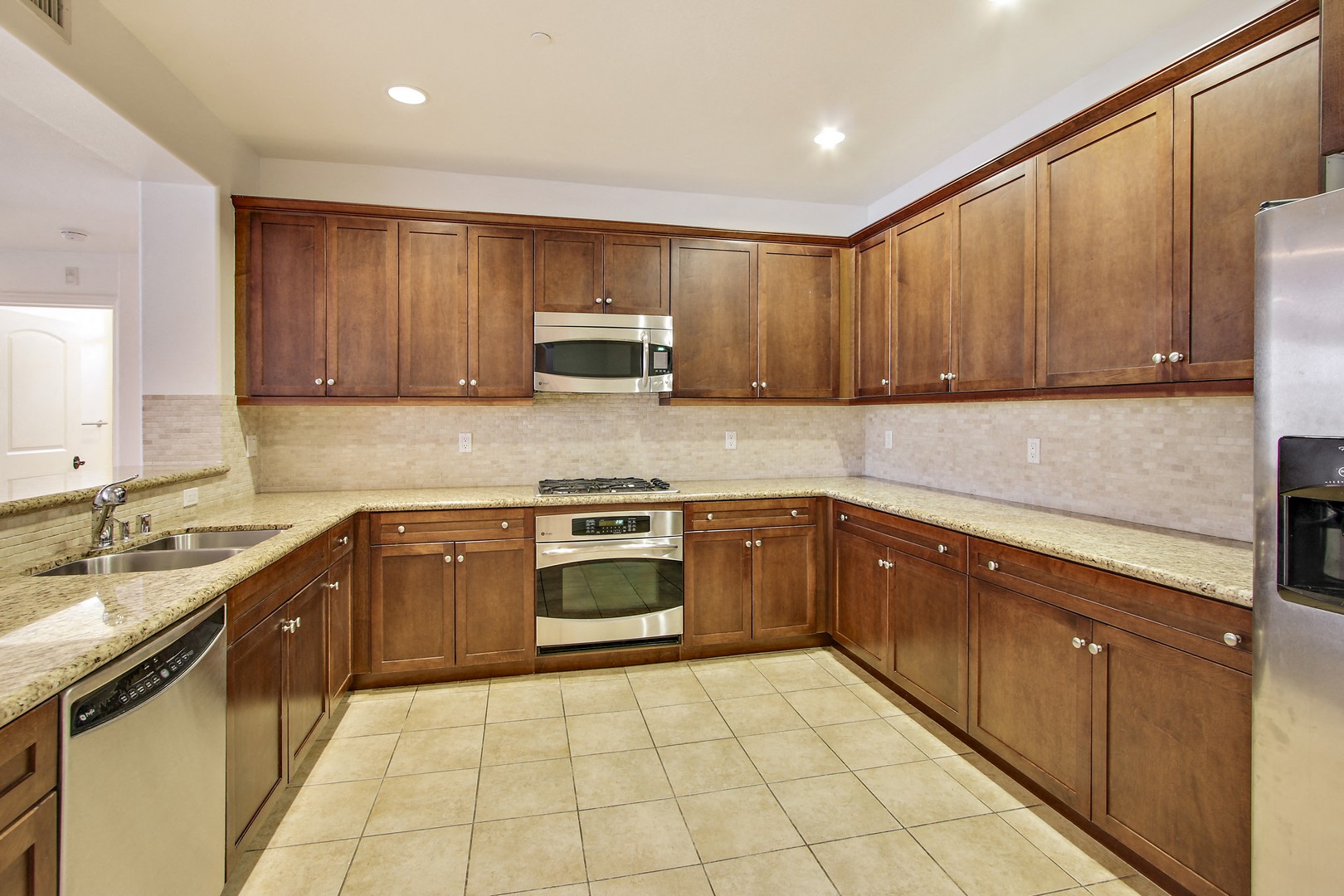 A kitchen with wooden cabinets and a tiled floor.