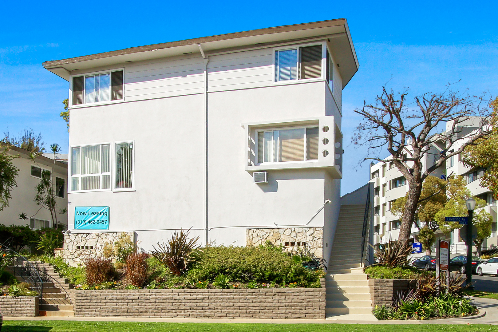 A white two-story building with a blue sign on the front.