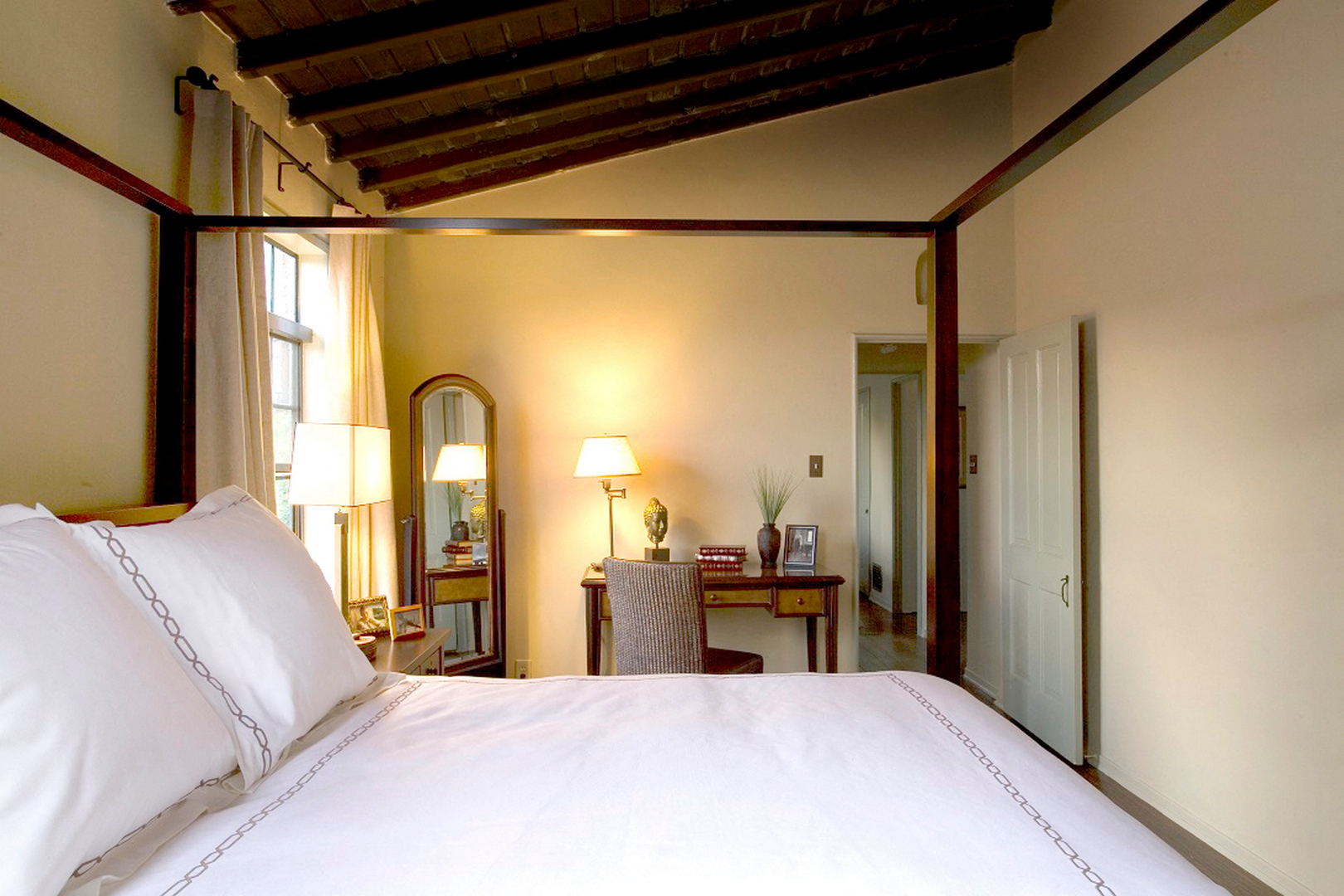 A bedroom with a large bed and a wooden ceiling.