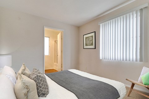 A bedroom with a bed, pillows, and a picture on the wall.