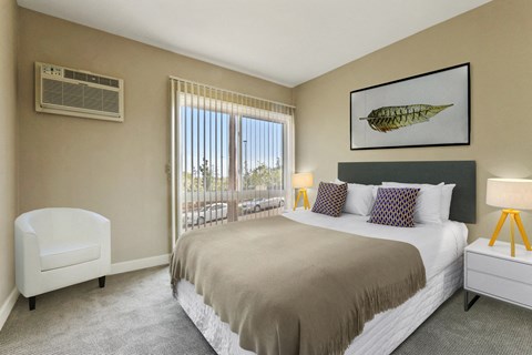A bedroom with a large bed and a chair.