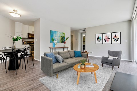 A living room with a grey couch, a coffee table, and a painting on the wall.