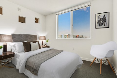 A bedroom with a large bed and a white chair.
