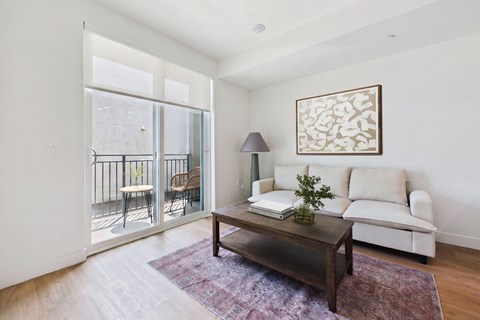A living room with a white couch, a coffee table, and a painting on the wall.